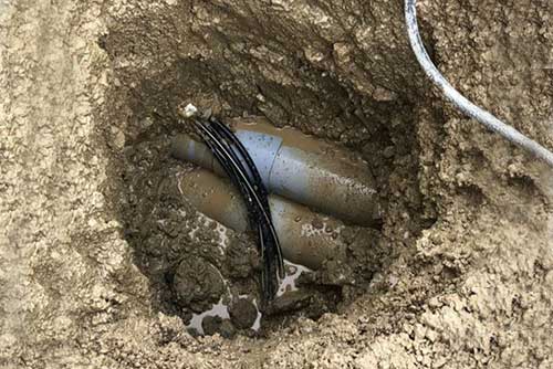 Utility potholing - a hole exposes pipes in the ground