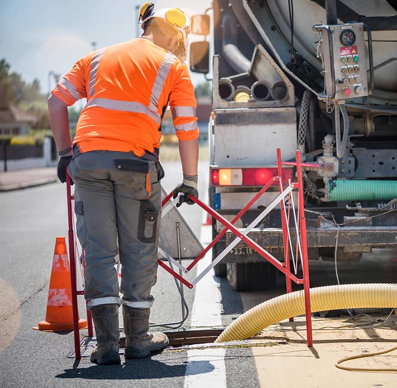 A worker using a vacuum truck to clean a sewer